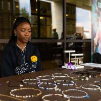 Student merchant looks over display of jewelry during Student Small Business Market.